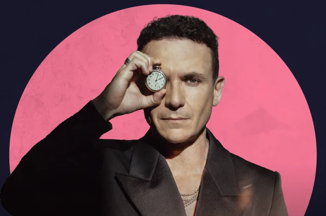 Fonseca sostiene un reloj de bolsillo frente a su ojo, sobre un círculo rosa.